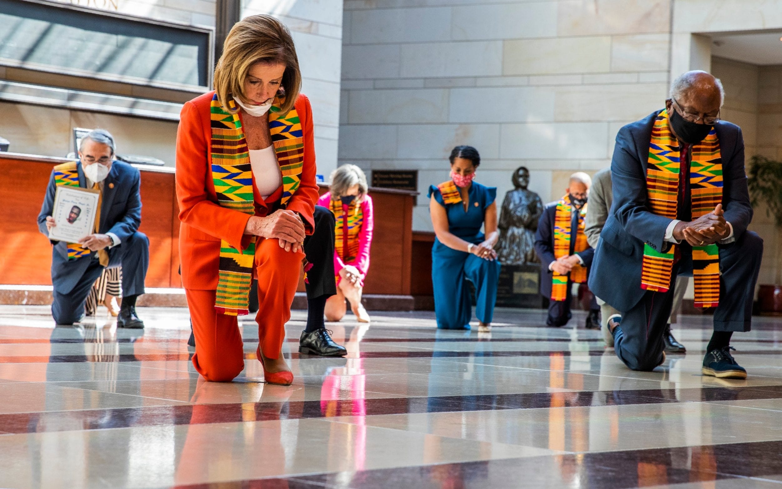 image of Nancy Pelosi and members of congress wearing kente cloth scarves and kneeling